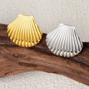Macro detail of gold and silver seashell rings on dark wood with polished ribbed texture
