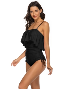 Detail of black one-piece swimsuit featuring large ruffled hem and side drawstring ties