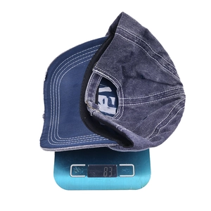 Distressed dark blue denim baseball cap weighing 83g on a digital scale for outdoor sports