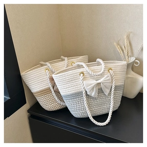Detailed view of woven tote bags featuring large white bows and gold metal ring handles