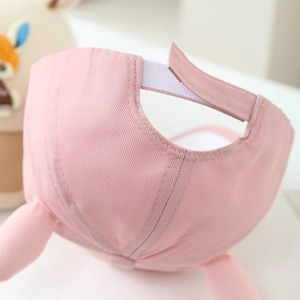 Detail view of pink kids' rabbit ear baseball cap with adjustable Velcro strap.