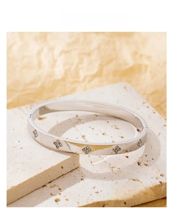 Macro detail of polished titanium steel clover bangle with sparkling zircon inlay