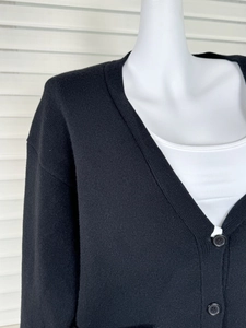 Detail of V-neck knit cardigan showing black buttons and premium ribbed fabric texture