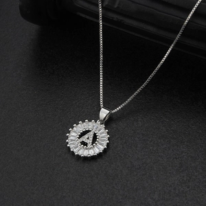 Macro view of silver necklace with circular pendant featuring letter A and zircon stones