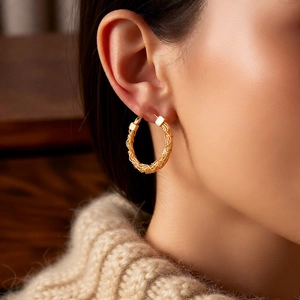 Close-up of model wearing 24k gold-plated hoop earrings with elegant woven texture