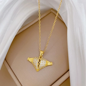 Macro detail of gold broken heart pendant with crystals on soft silk background