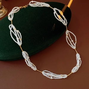 Primer plano de collar de perlas blancas con cadena dorada en cojín de terciopelo