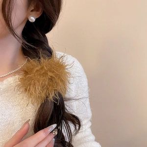 Detailed close-up of warm brown plush hair scrunchie on soft long wavy hair