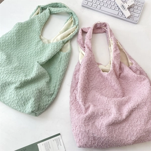 Macro detail of textured popcorn fabric tote bags in mint green and soft pink