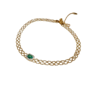 Vintage style gold bracelet with oval green gemstone and pavé rhinestones on white background