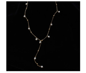 Detailed macro view of gold-plated Y-shaped necklace with white pearls on black velvet