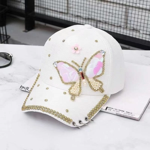 Vue détaillée d'une casquette blanche avec papillon en paillettes et strass dorés