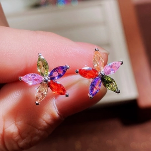Close-up of a colorful flower stud earring with marquise-cut gems on fingers