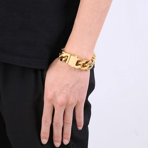 Macro shot of a 20mm chunky gold Cuban link bracelet on a male wrist with buckle detail
