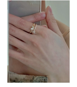 Detail of stacked gold rings featuring a white mother of pearl butterfly and floral accents