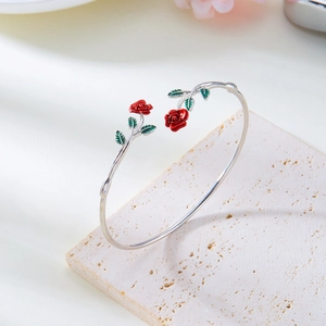 Detail view of silver rose bangle with red enamel flowers and green leaves on stone base