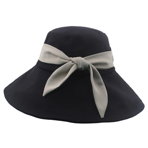 Dettaglio cappello da sole nero a tesa larga con nastro a fiocco decorativo color tortora