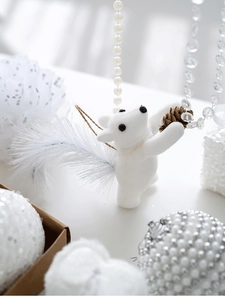 Detail of white flocked Christmas animal ornament with natural pinecone and feather tail