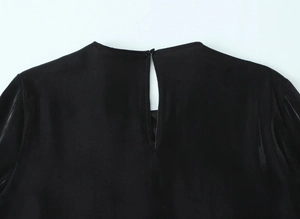 Detail view of black velvet shirt neckline with back button and teardrop cutout