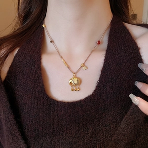 Dettaglio della collana con ciondolo a elefante dorato e perline rosse intrecciate