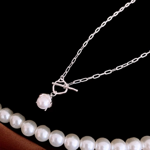 Elegant paperclip chain necklace with a pearl pendant and OT buckle on a dark background