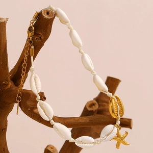 Détails de breloques étoile de mer et coquillage dorés 18K sur un bracelet de cheville