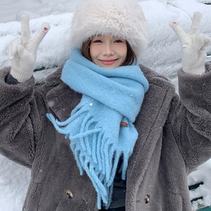 Cozy winter set with light blue knitted scarf, beige plush hat, and white gloves in snow