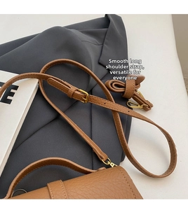 Detail of brown litchi pattern leather shoulder strap with gold metal buckle and lobster clasp