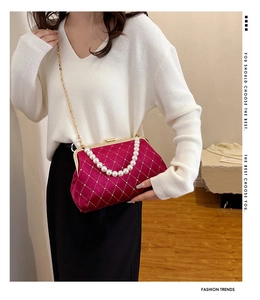 Detail of rose red velvet handbag with pearl handle, diamond quilting and gold chain
