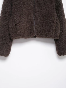 Detailed close-up of dark brown lamb wool jacket featuring silver zipper and hem texture