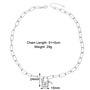 Macro detail of silver paperclip chain necklace with zircon pavé lock and key pendant