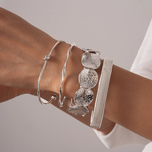Detail of silver geometric bangle set showing layered textures on model wrist