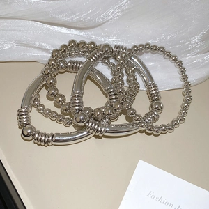 Vue détaillée de quatre bracelets en métal argenté sur un fond de soie blanche