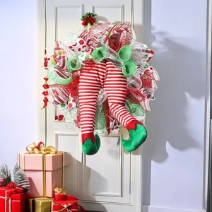 Festive Christmas wreath with elf legs on a white door with holiday gift boxes