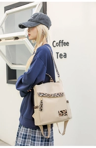 Detail of beige backpack featuring leopard print flap and decorative tassel in a cafe setting