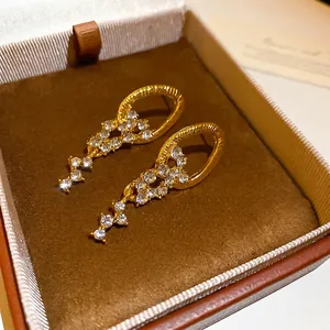 Elegant gold tassel earrings with zircon studs in a luxury jewelry box display
