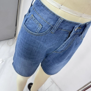 Detail view of denim shorts showing blue washed fabric with yellow contrast stitching