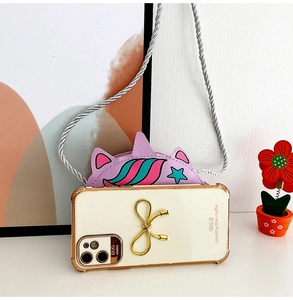 Detail of off-white phone case with gold bowknot ornament and purple unicorn bag accessory