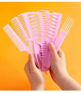 Hands holding a set of eight pink professional plastic hair combs on orange background