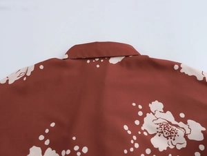 Détail du col de chemise caramel avec imprimés floraux blancs et texture de tissu lisse