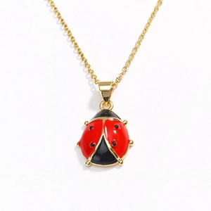 Detailed close-up of a red ladybug pendant with golden metal edges on a white background