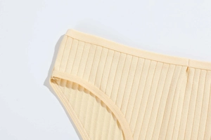 Macro detail of pale yellow ribbed cotton panties showing fine stitching and soft texture
