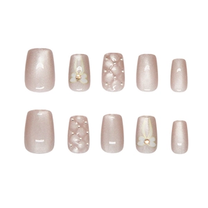 Faux ongles rose champagne avec motifs nœuds et textures 3D à perles