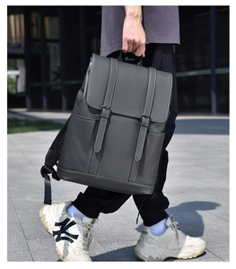 Detail of dark grey business backpack with double buckle flap in outdoor urban setting