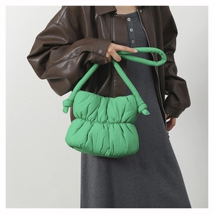 Detail of green ruched cloud bucket bag with knotted handle shown on shoulder