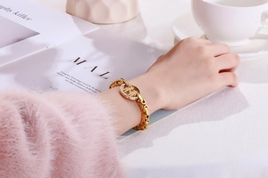 Close-up of gold chain bracelet featuring a round boy-girl silhouette pendant with diamonds