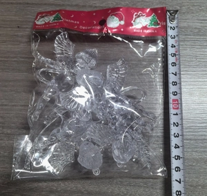 Detailed close-up of 4 transparent acrylic angel ornaments in retail packaging with ruler
