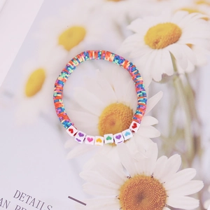 Detailed macro view of colorful rainbow Heishi beads and white heart patterned bead bracelet