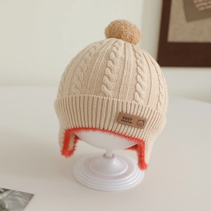 Detail of baby knit hat showing soft beige cable stitch and orange faux fur lining