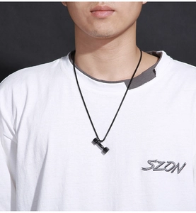 Detail of a matte black dumbbell pendant necklace on a male model with a dark chain